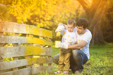 Cute little boy and his father painting wooden fence together on sunny day in nature sbi 305129508